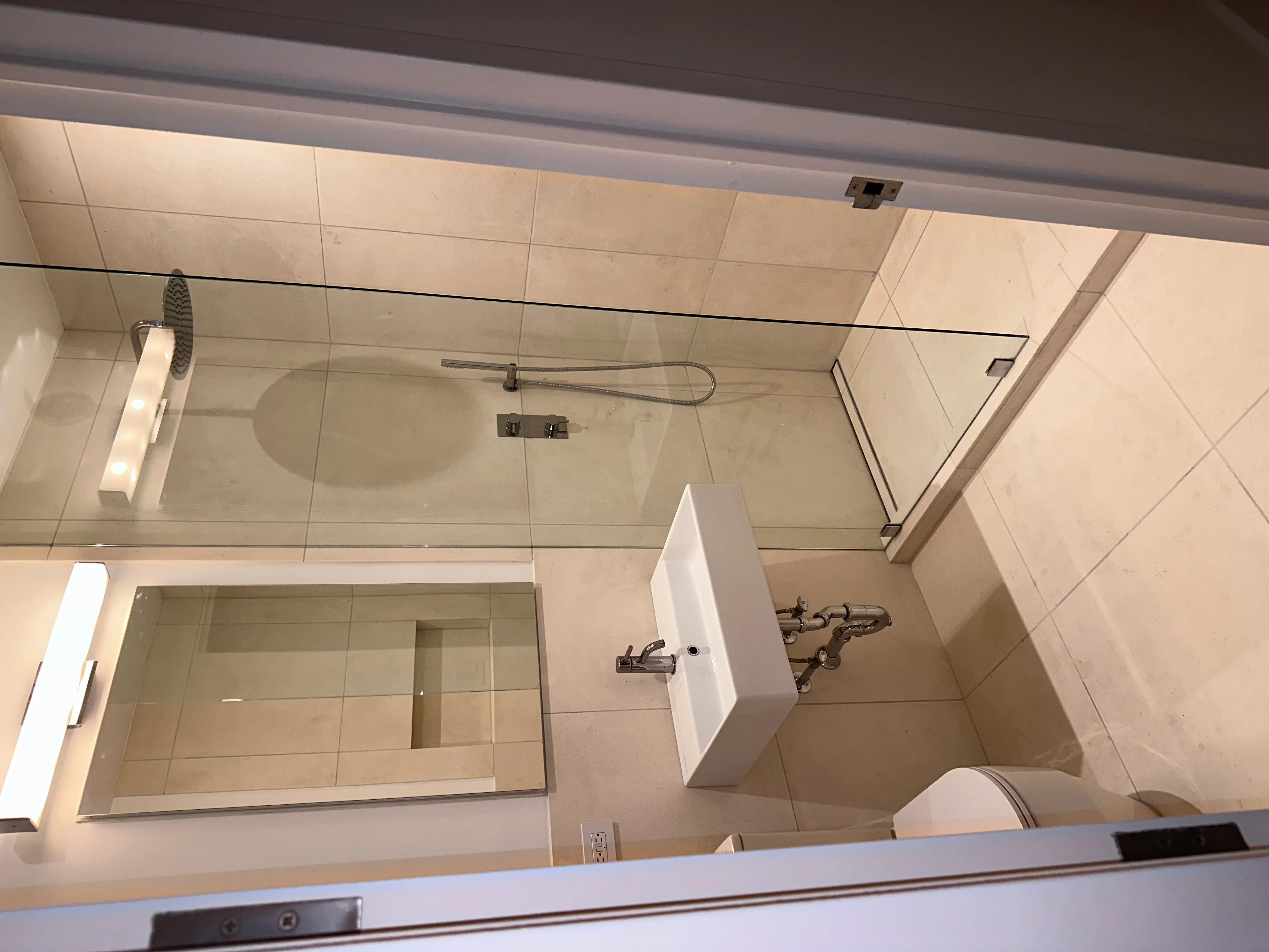 Modern bathroom with large ceramic tiles, frameless glass shower, and chrome fixtures