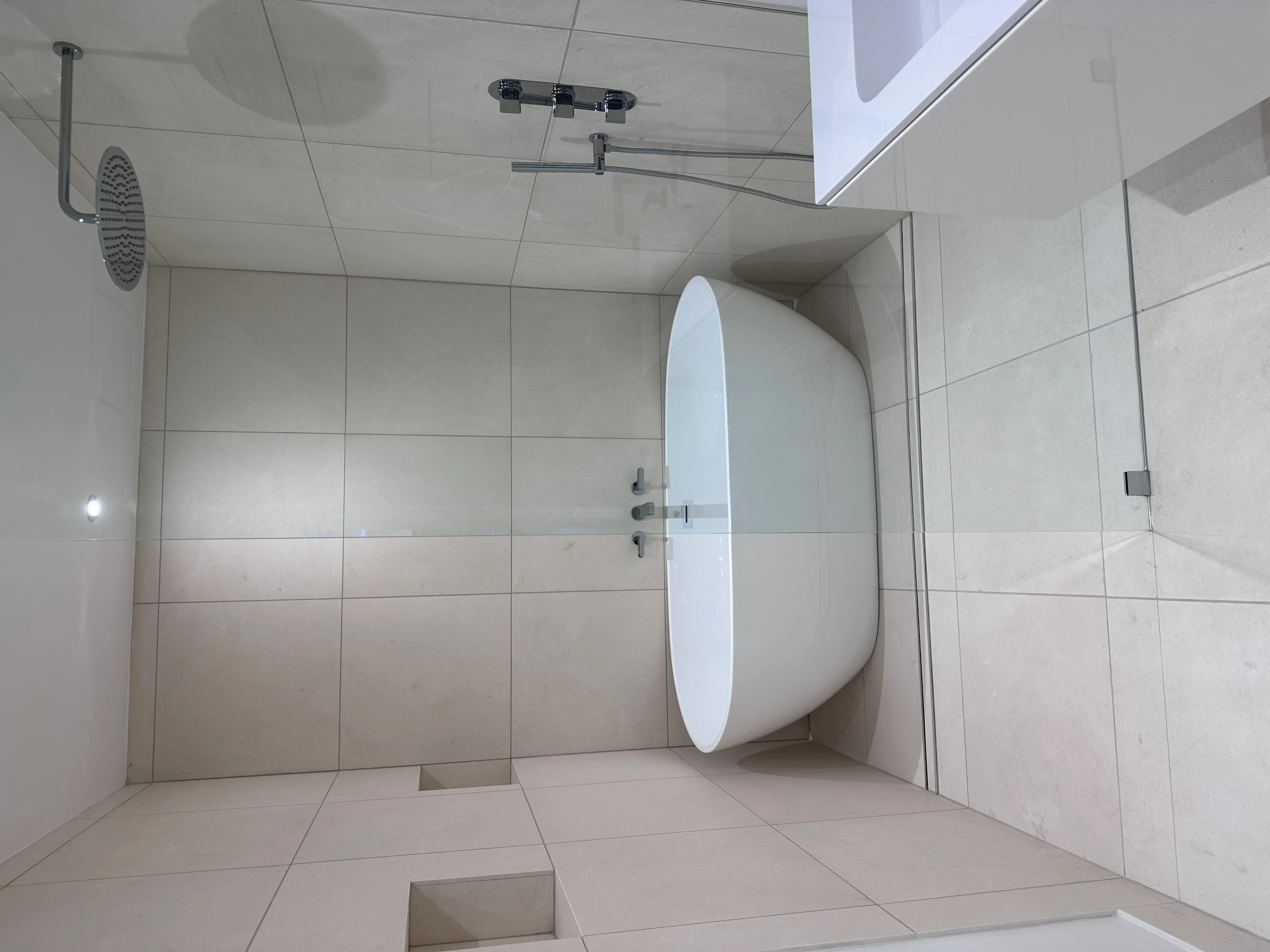 Contemporary bathroom with white tile walls, walk-in shower, and frameless glass door