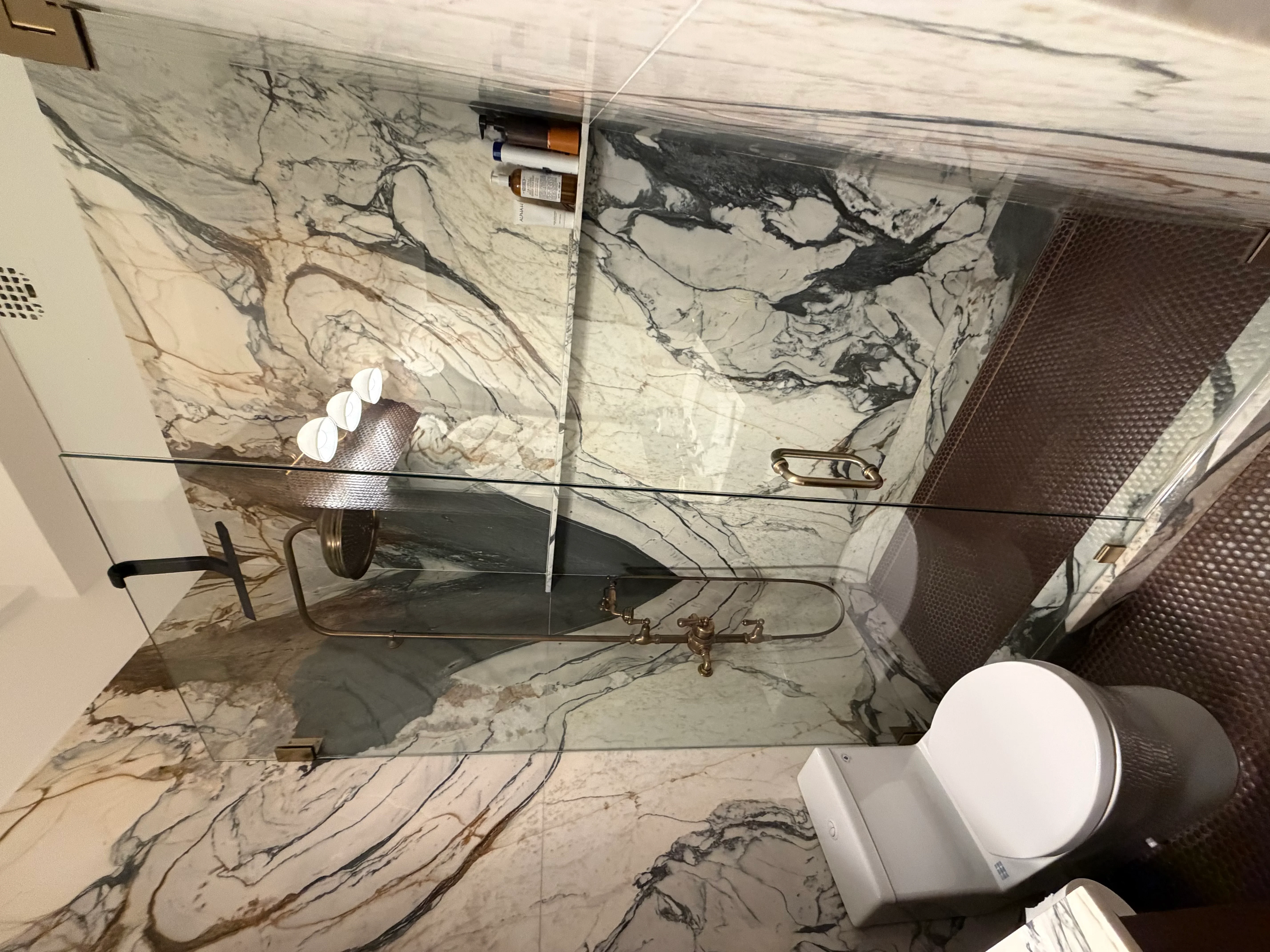 Marble bathroom with veined tile walls, vanity, mirror, and modern fixtures