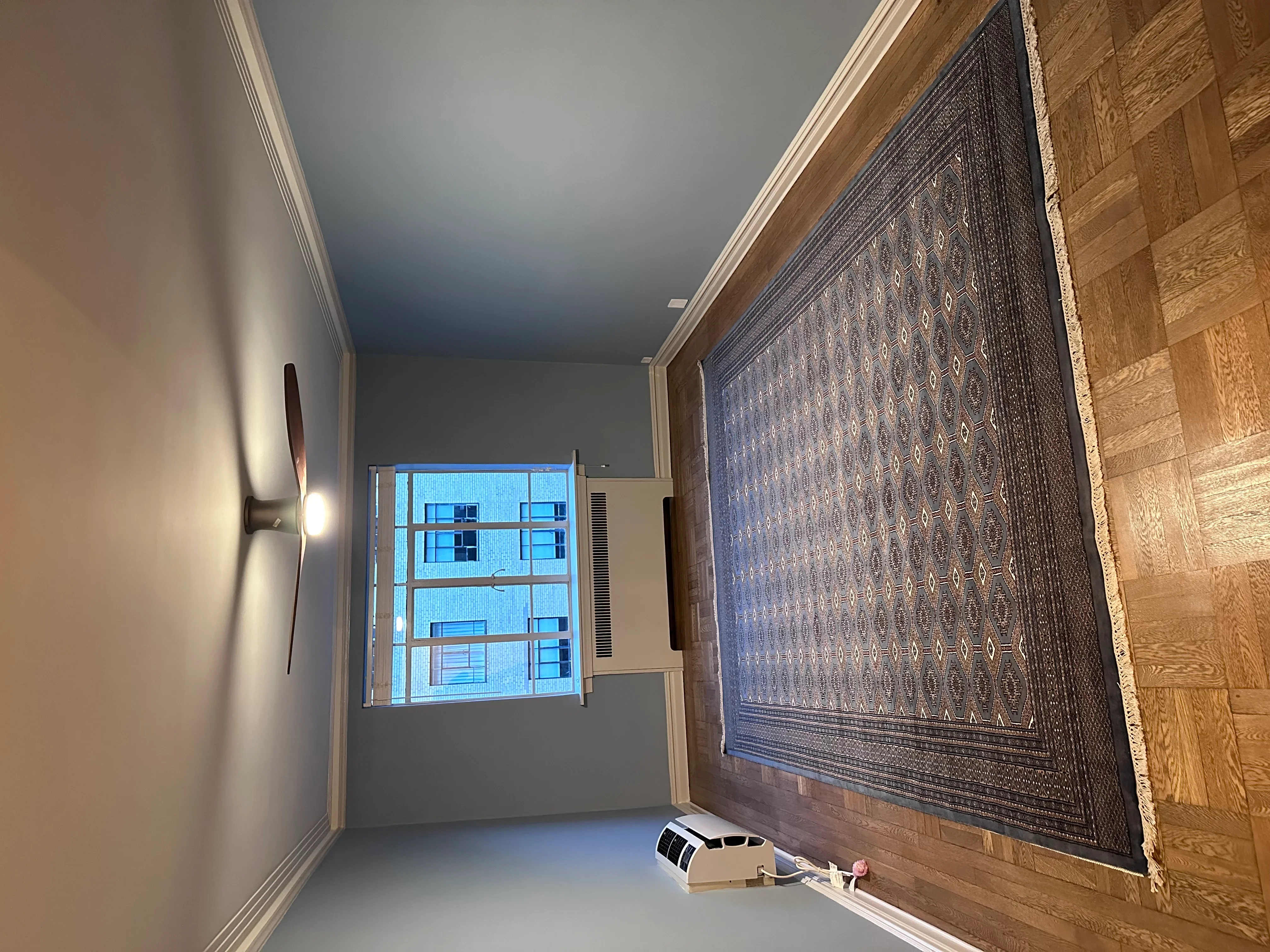 Interior room with custom wood-framed window, blue-patterned area rug, and finished drywall