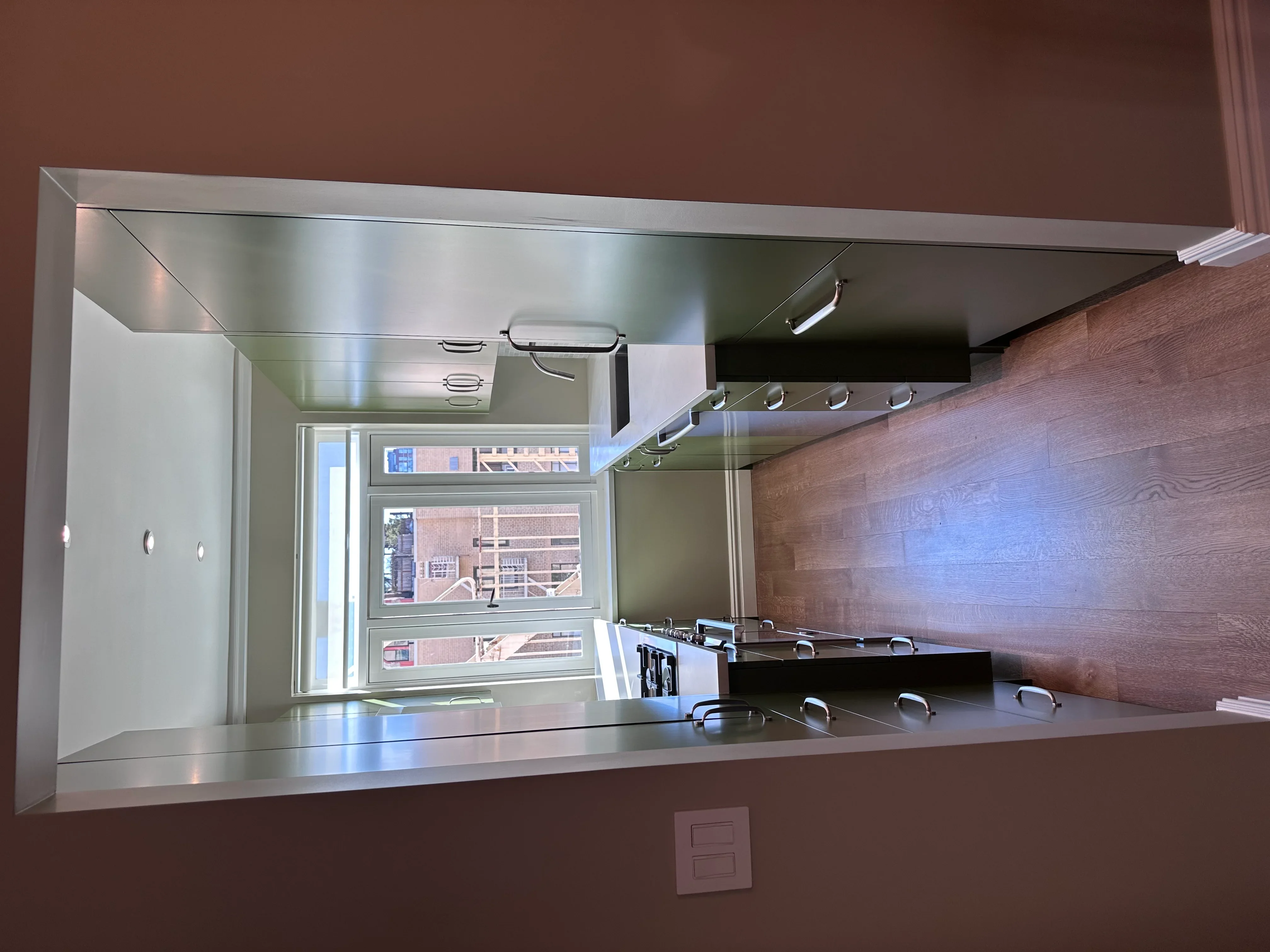 Modern kitchen with wood cabinetry, stainless steel counters, and recessed lighting