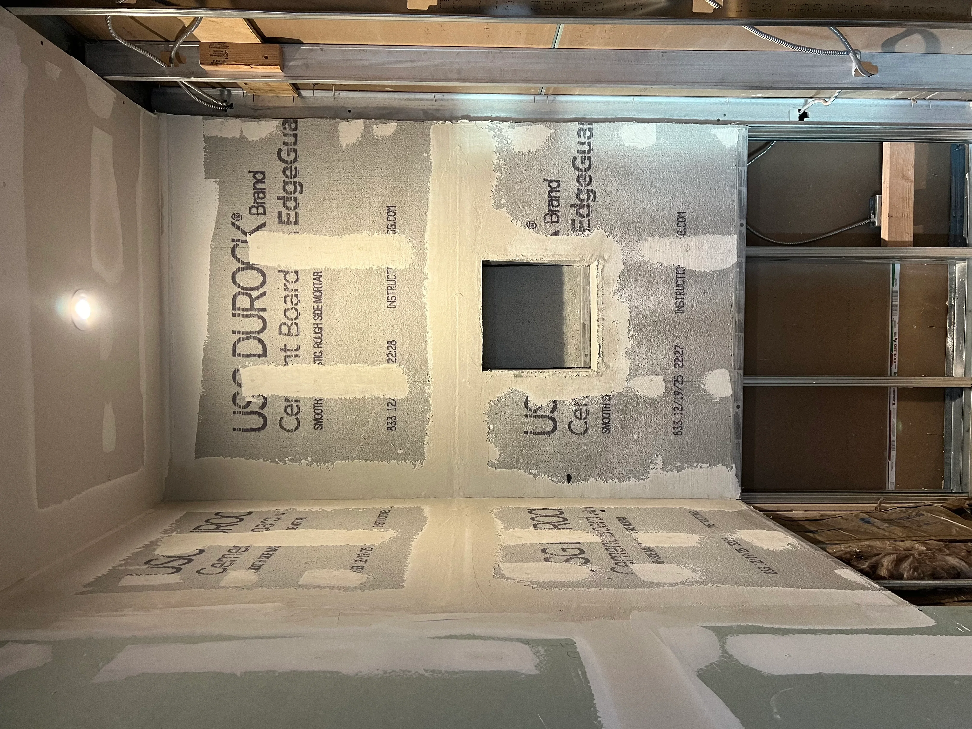 Drywall installation with taped seams and outlet cutout in residential interior