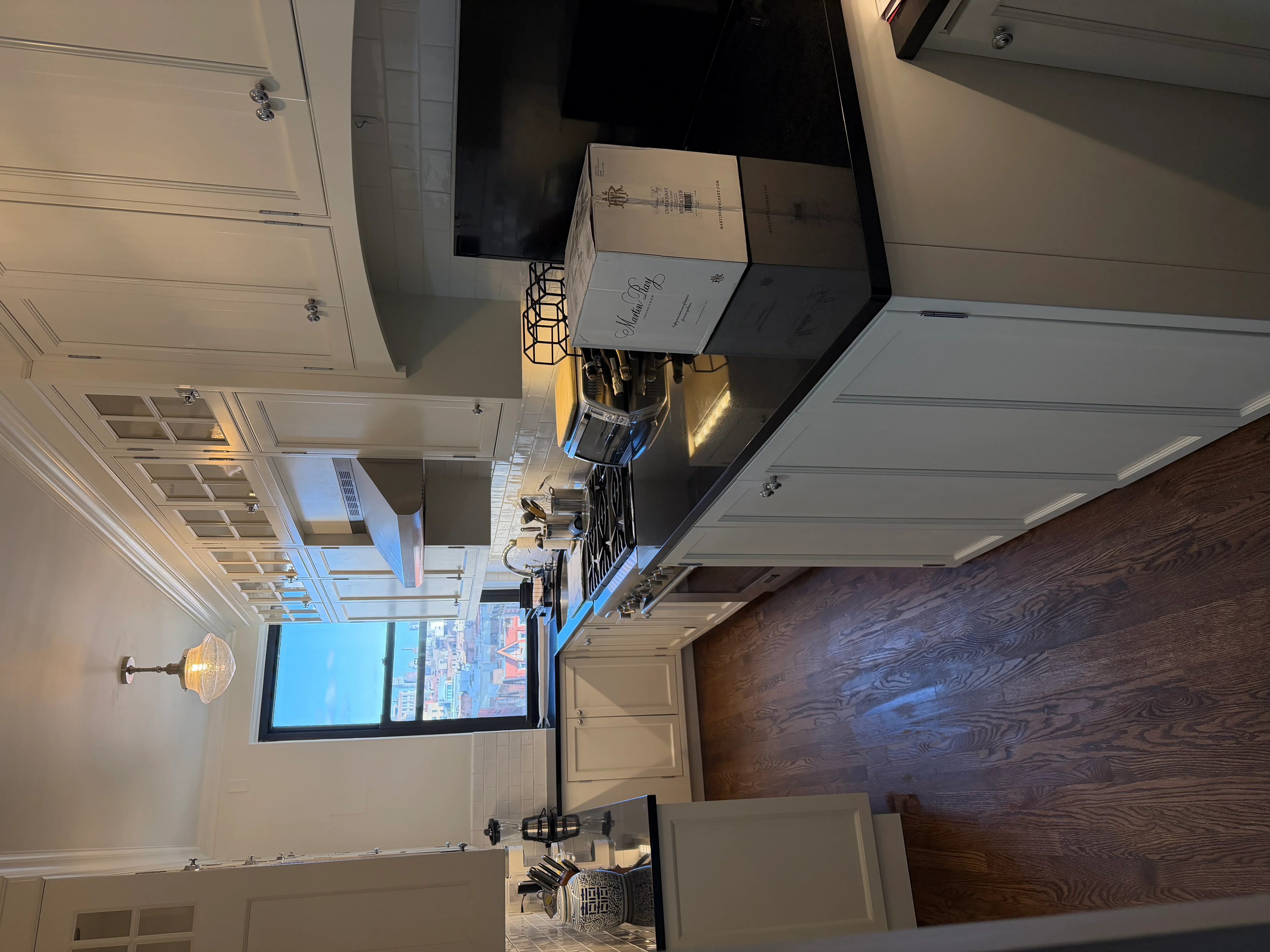 Modern kitchen with white cabinetry, dark counters, and coffered ceiling in open dining area