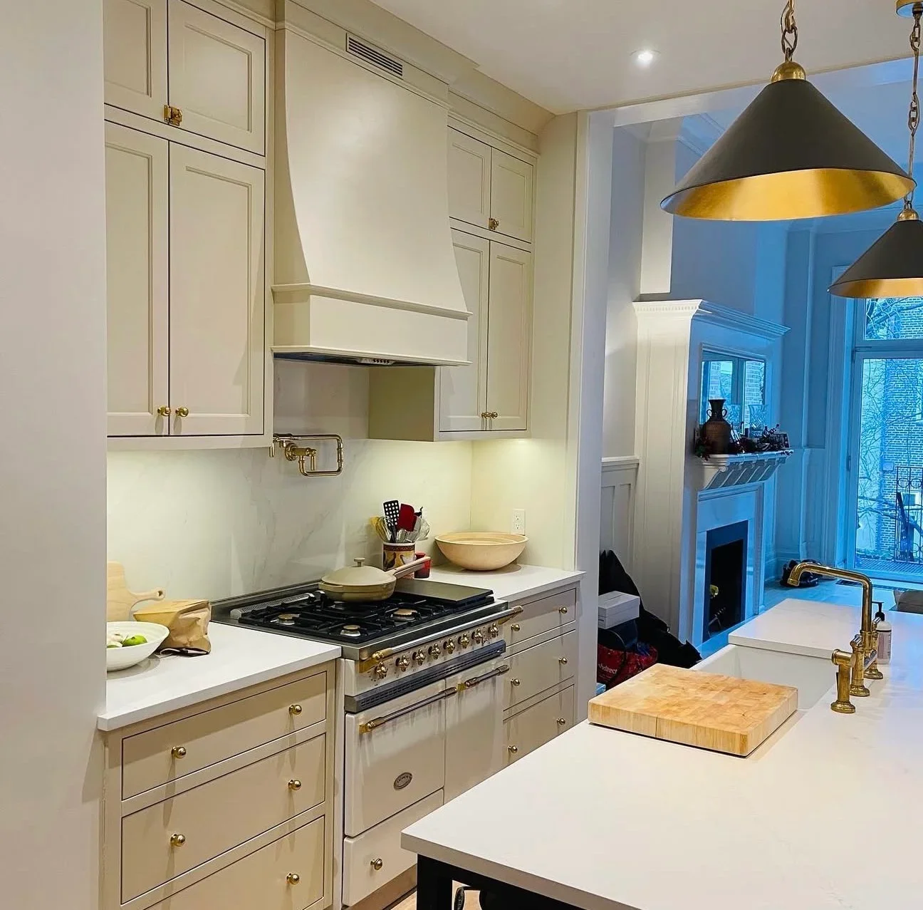 Modern kitchen with cream cabinetry, white counters, gas range, and brass fixtures