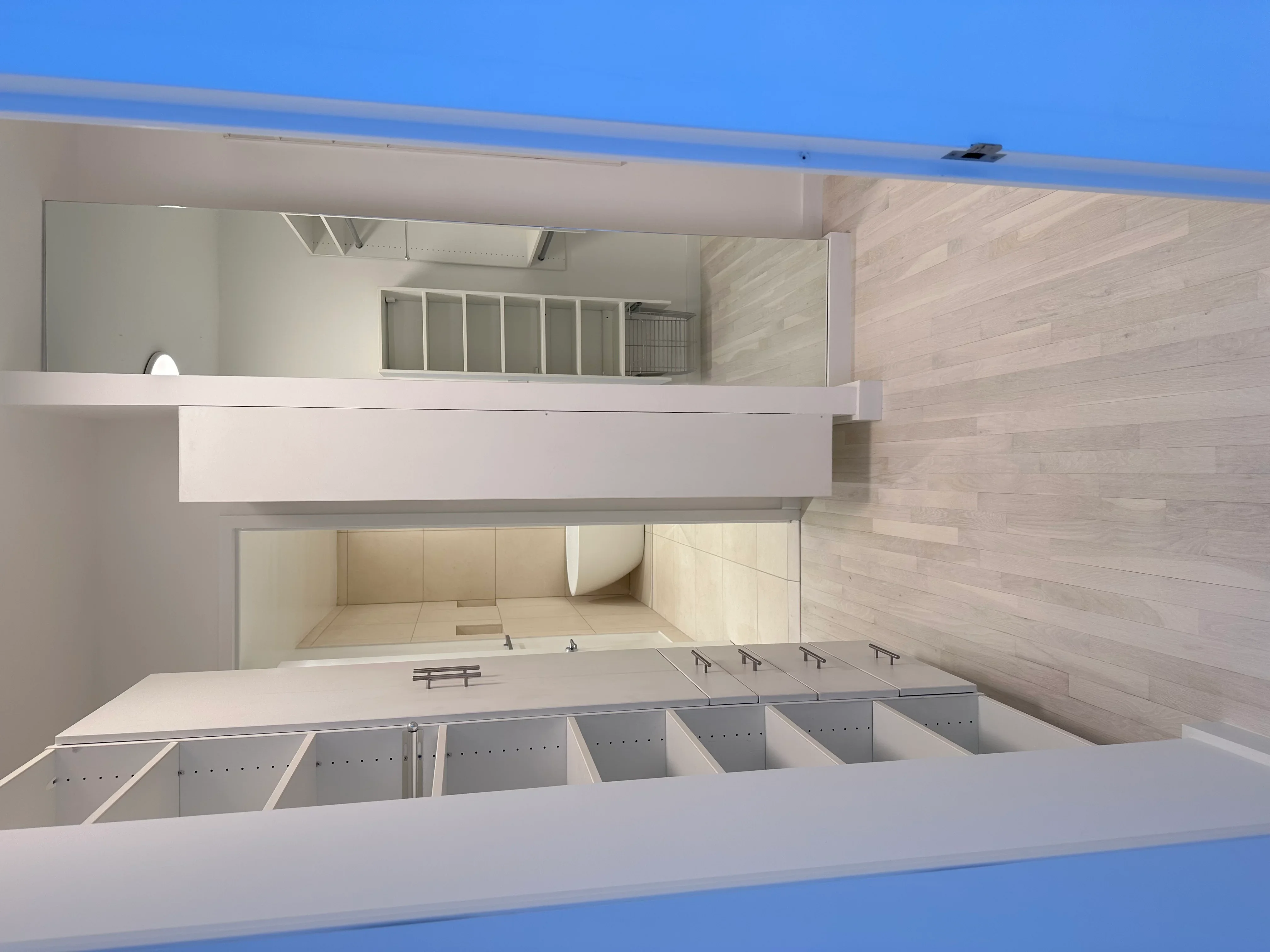 Modern kitchen interior with white cabinetry, wood paneling, and organized storage compartments