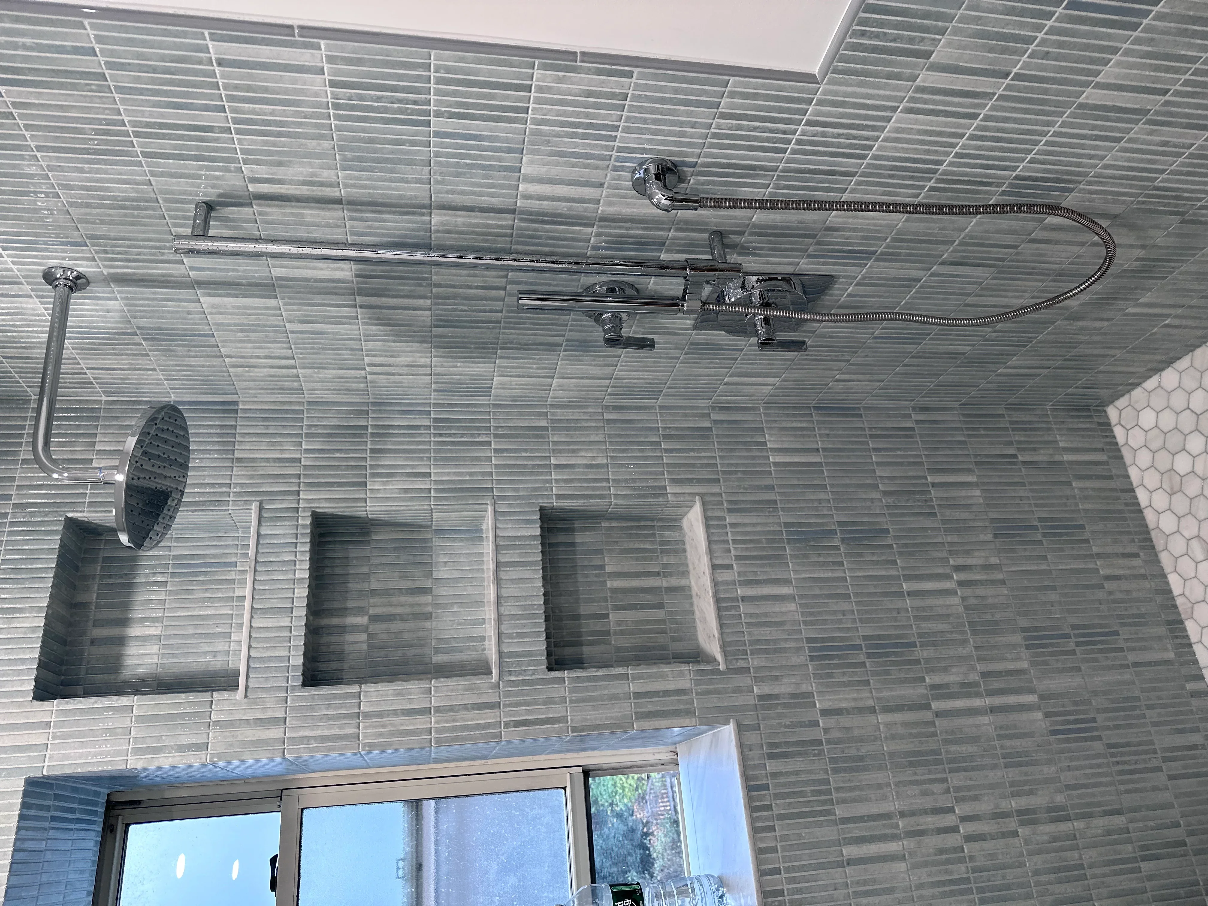 Modern shower with gray linear tile, dual showerheads, and built-in niches