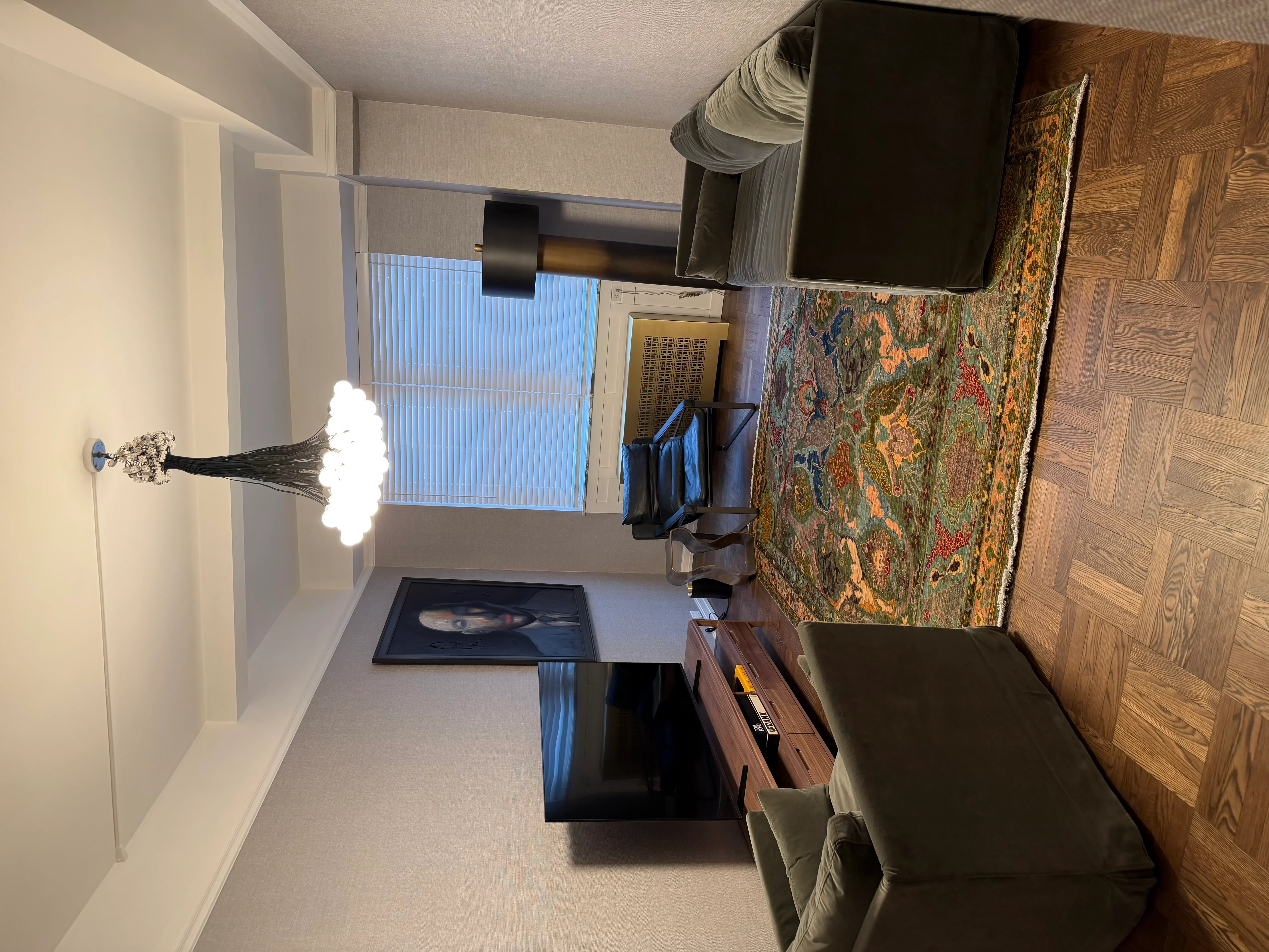 Renovated living room with painted walls, hardwood flooring, mounted TV, and window blinds