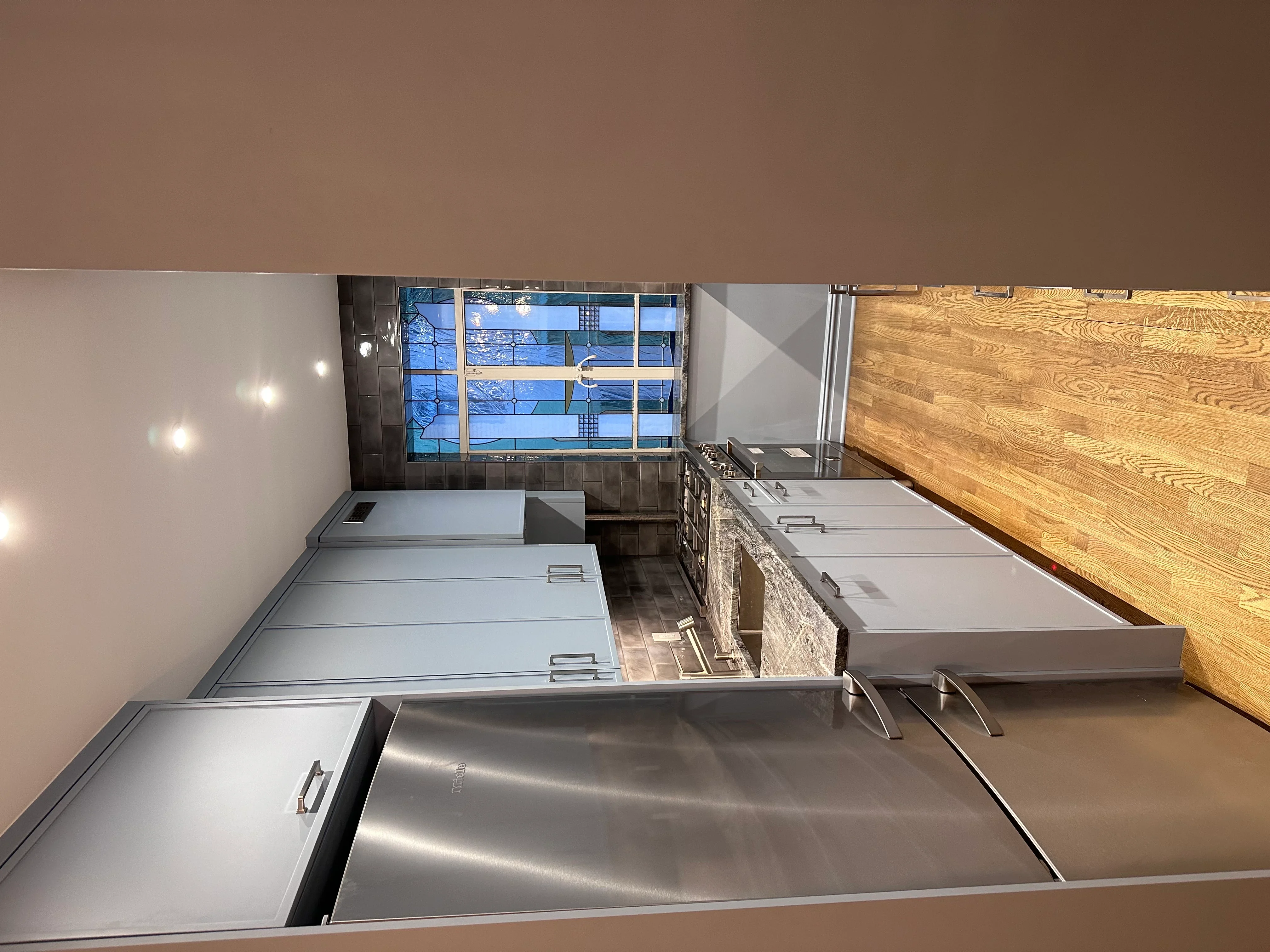 Commercial kitchen with stainless steel equipment, recessed lighting, and wood accent wall