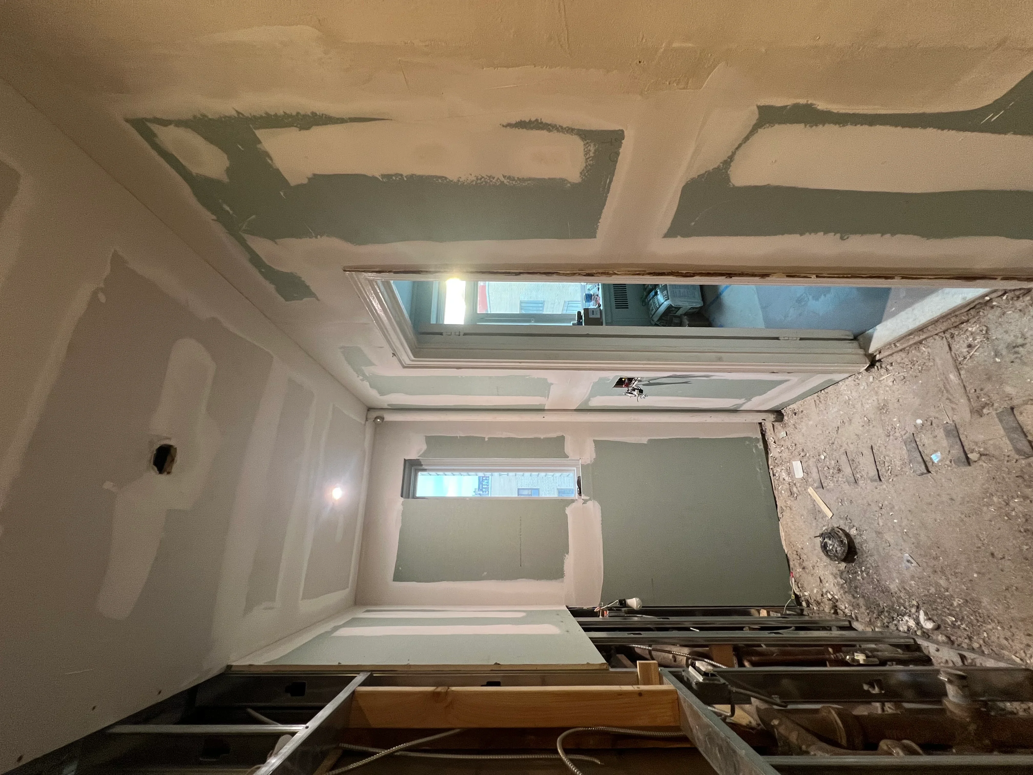 Drywall installation in progress with metal ceiling framing and window openings