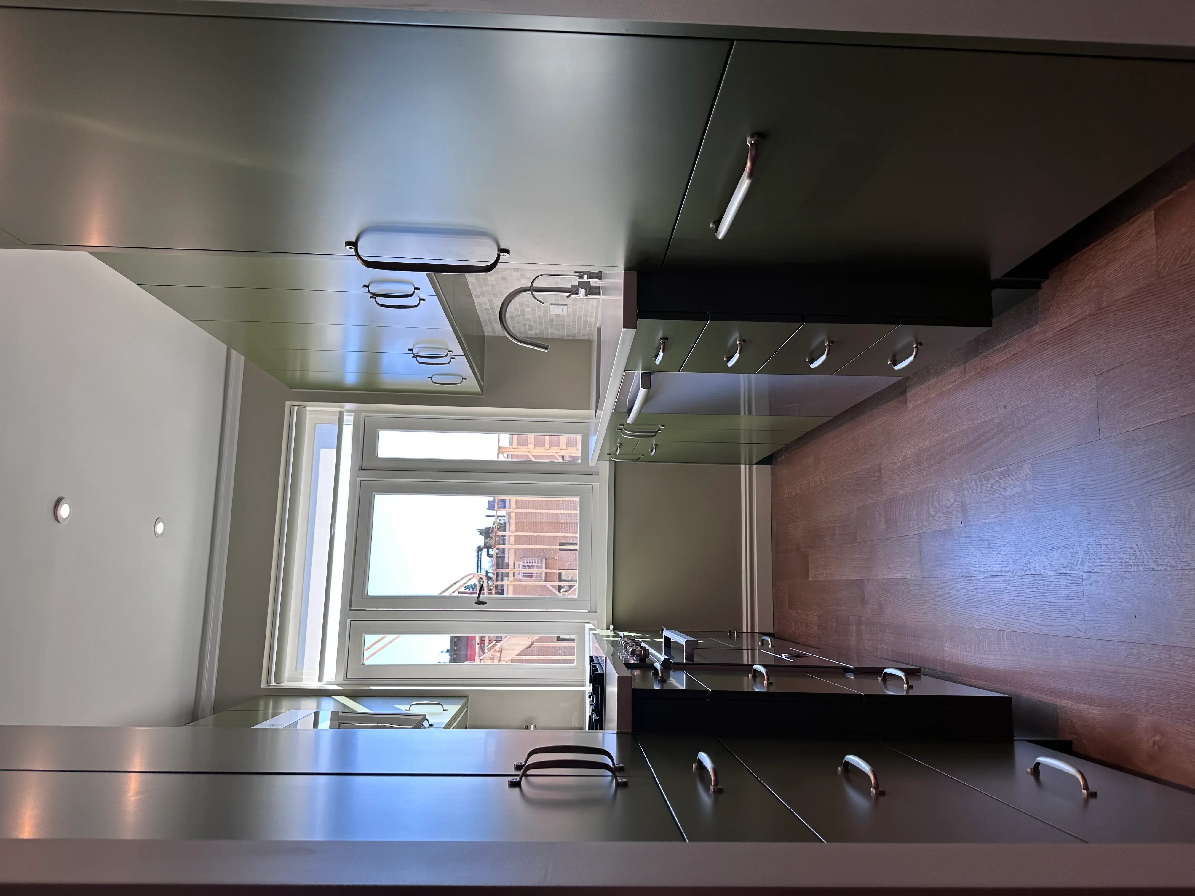 Modern kitchen with dark cabinetry, stainless steel counters, and wood accent wall
