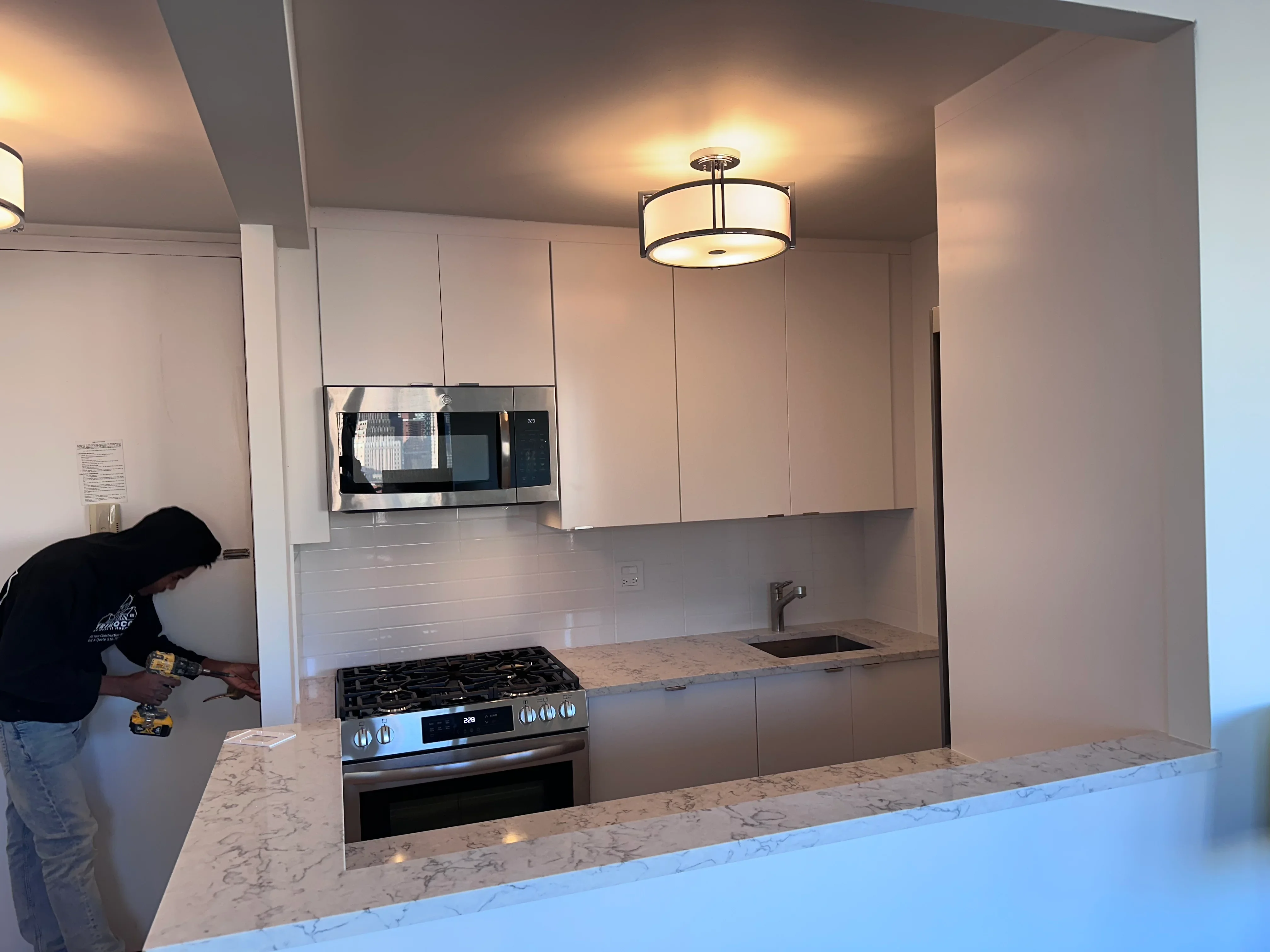 Modern kitchen with white cabinets, marble counters, and stainless steel appliances