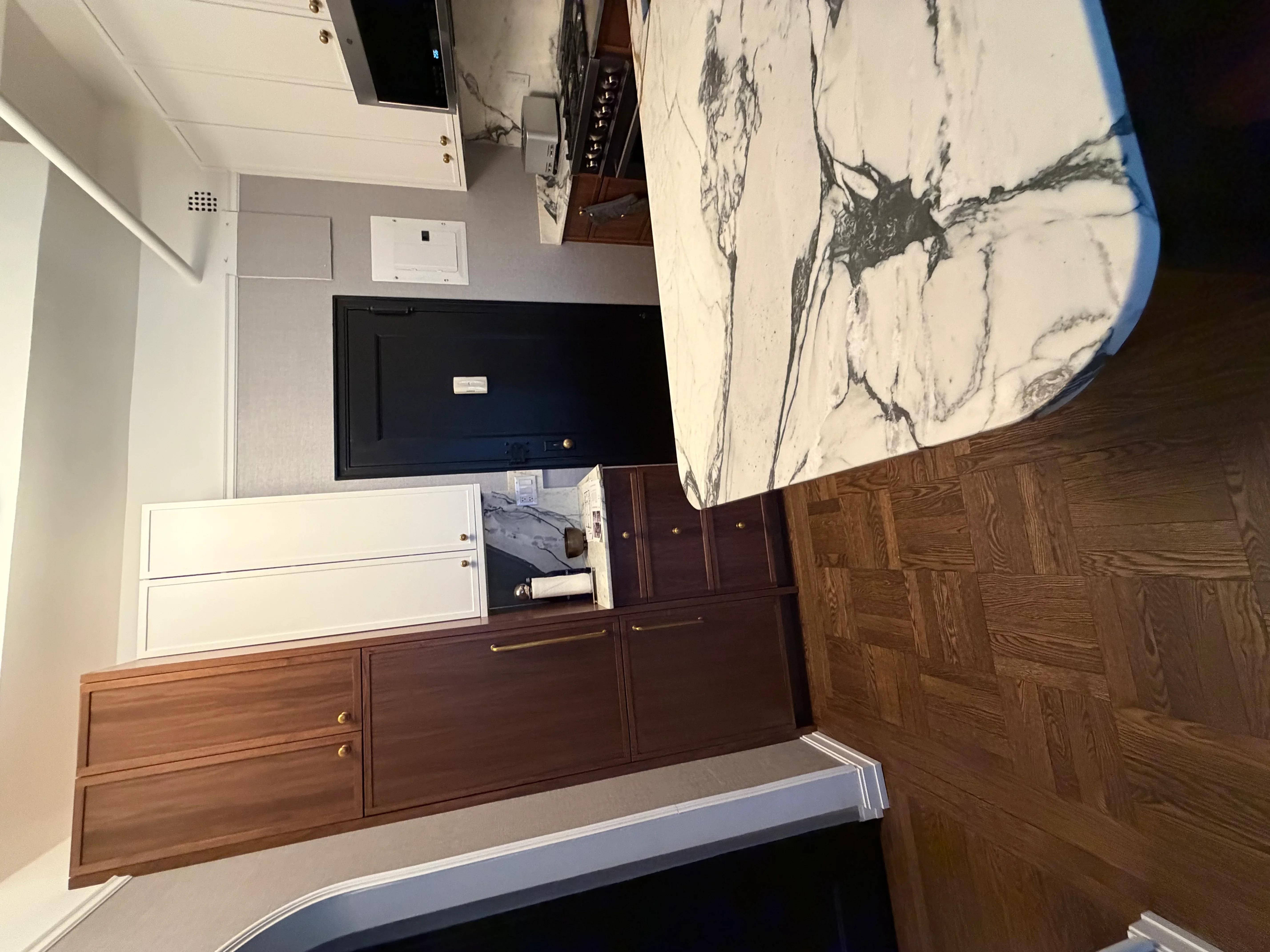 Master bedroom with dark wood cabinetry, marble countertops, and wall-mounted TV
