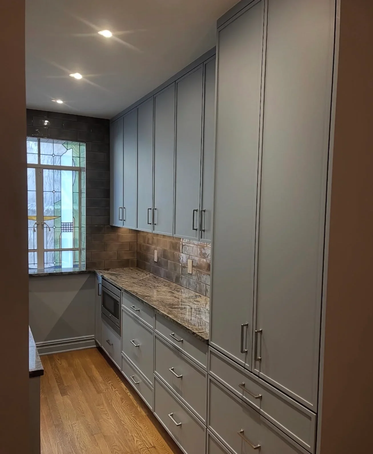 Modern kitchen with gray cabinetry, granite counters, and subway tile backsplash