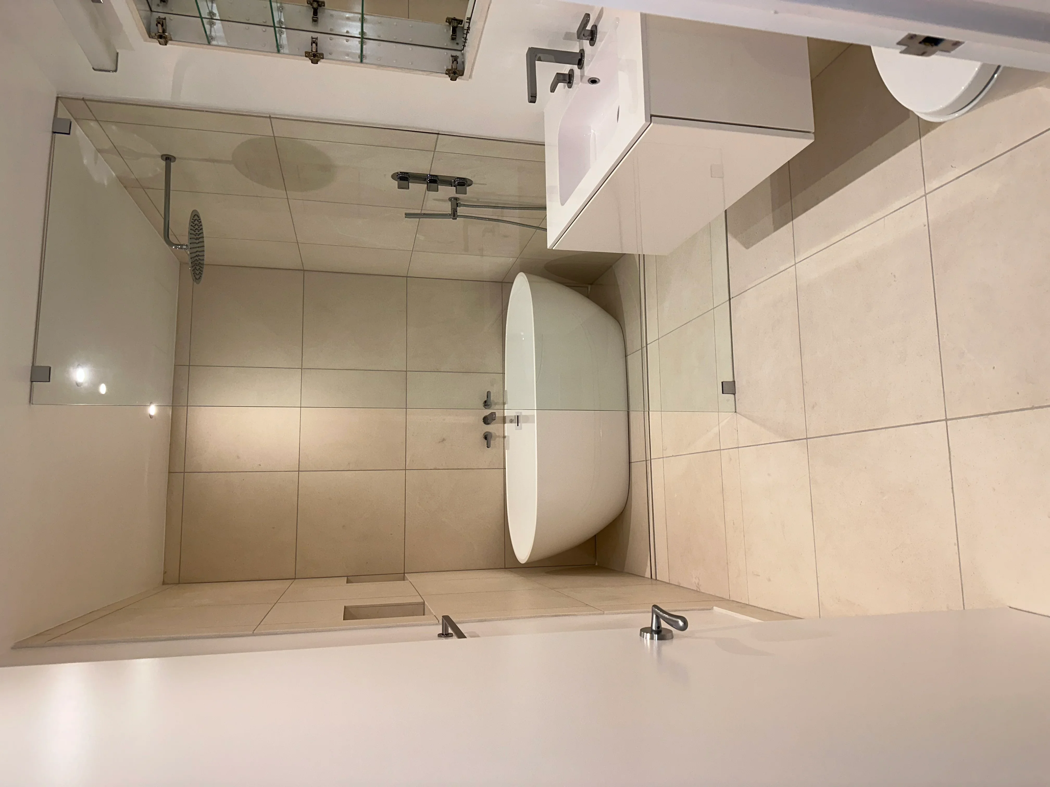 Modern bathroom with large tile walls, frameless glass shower, and floating vanity