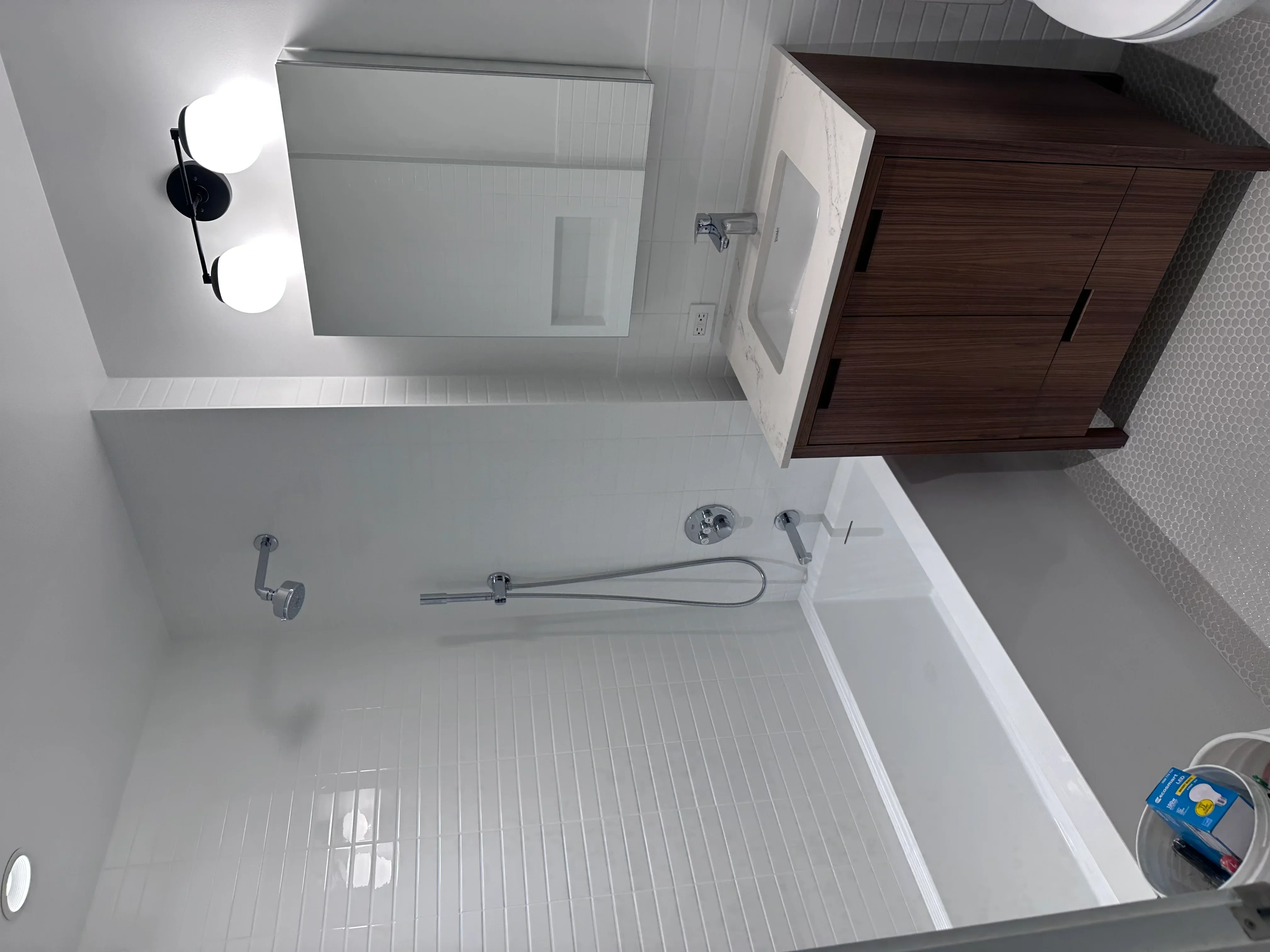Newly renovated bathroom with white subway tile floor, chrome fixtures, and dark wood vanity