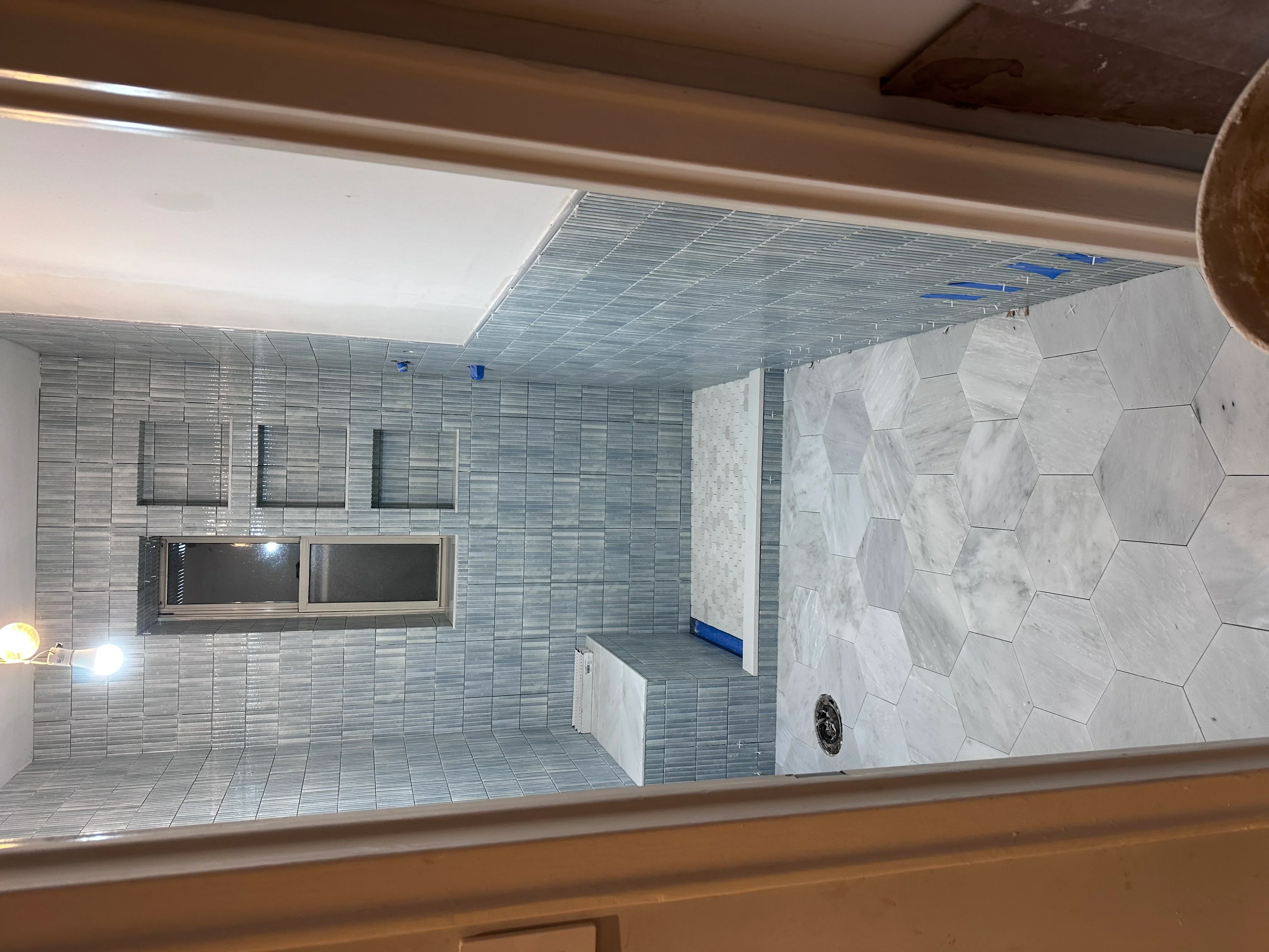 Modern bathroom with gray linear tiles, marble hexagon accent wall, and recessed lighting