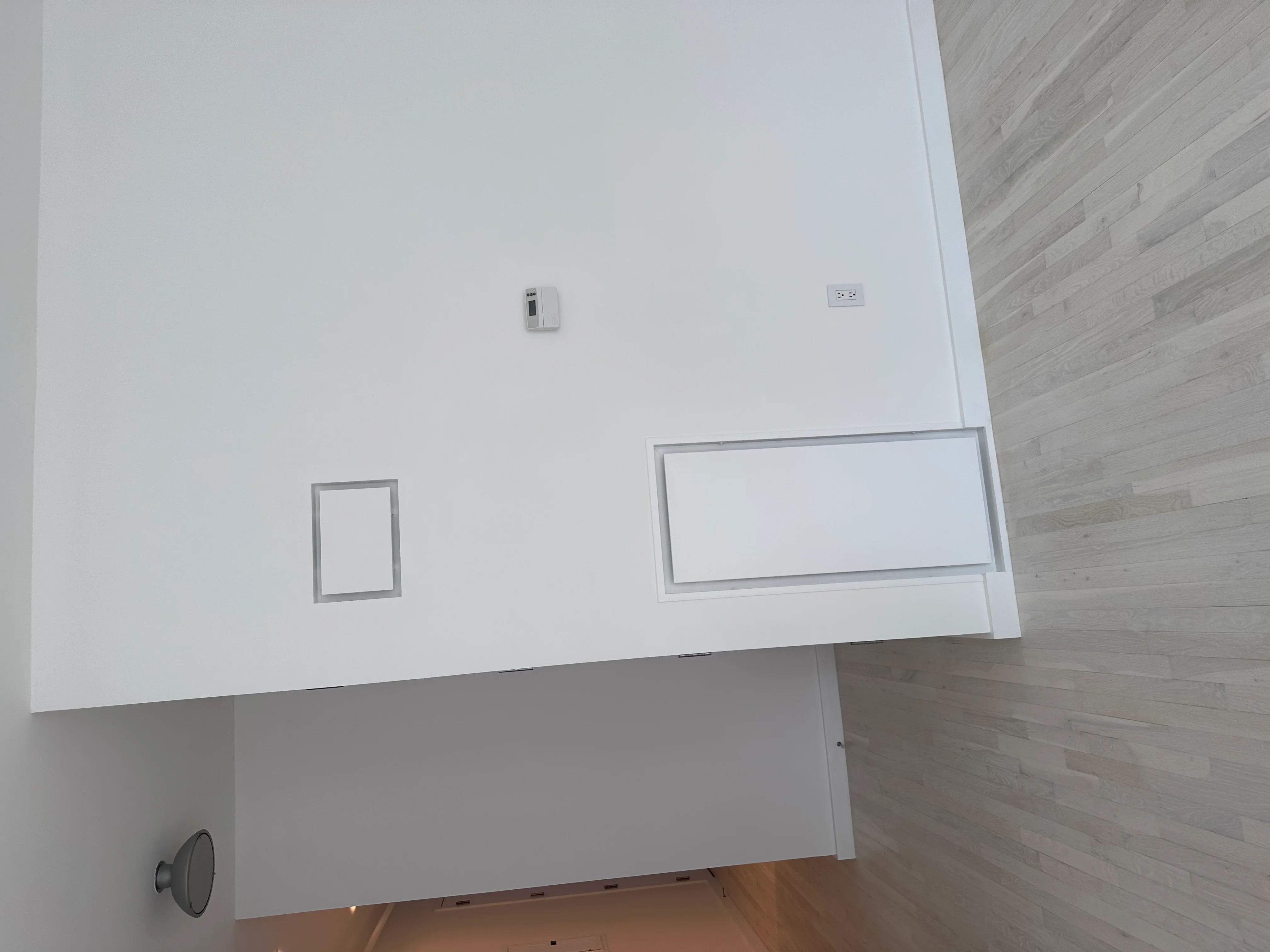 White drywall walls with electrical outlet and thermostat boxes installed during interior construction