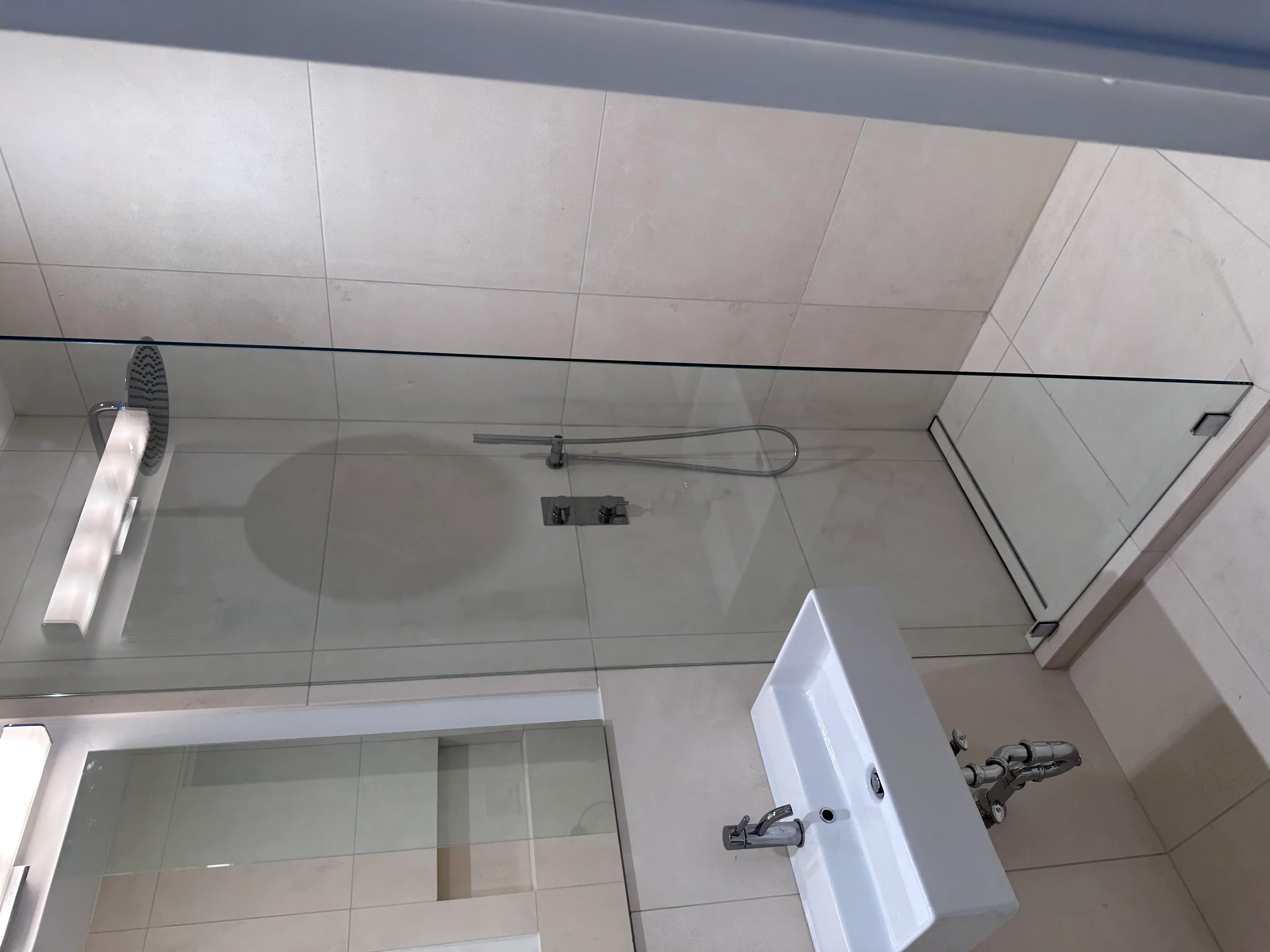 Modern bathroom with white tile walls, glass shower enclosure, and white vanity
