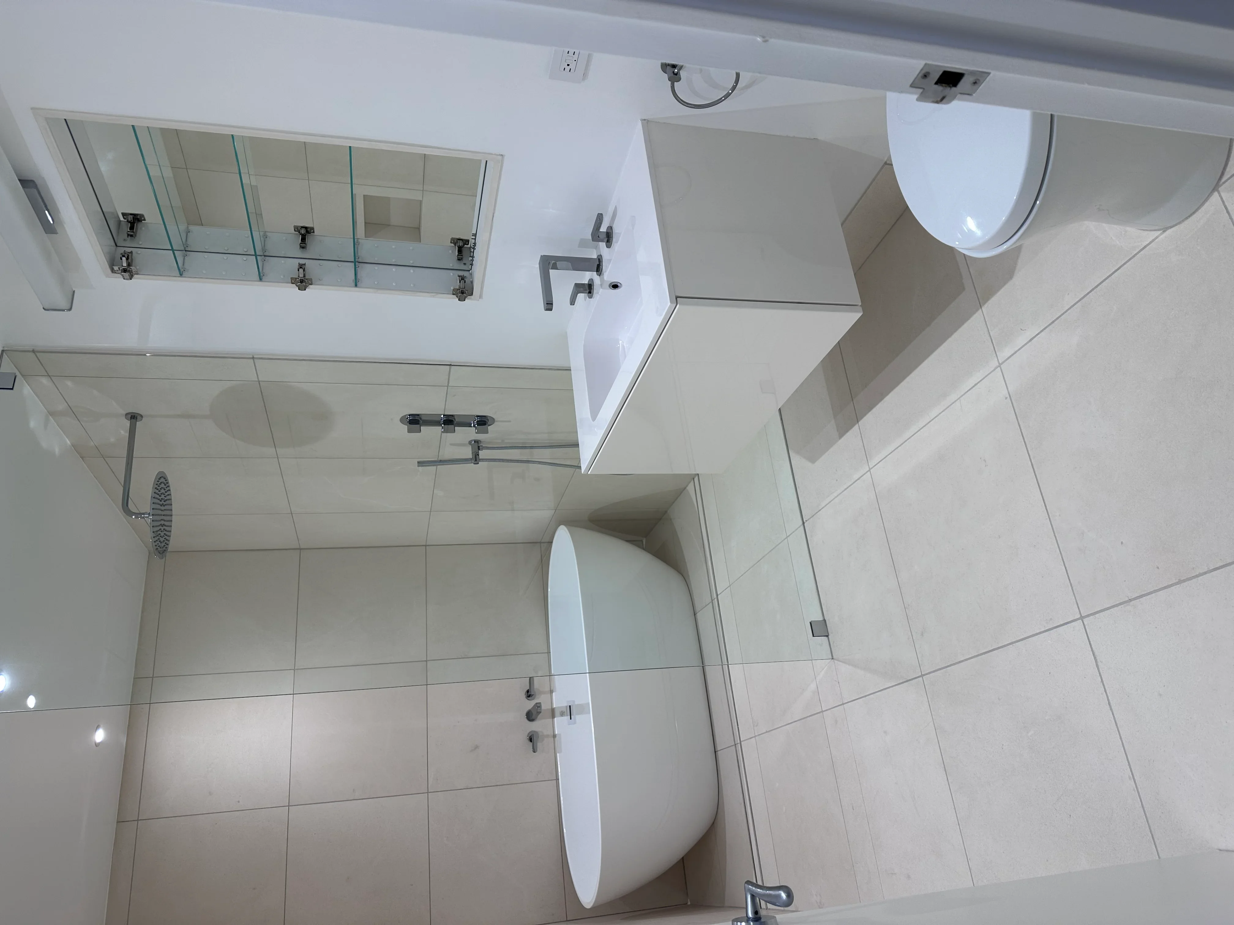 Modern bathroom with white tile, glass shower enclosure, and floating vanity
